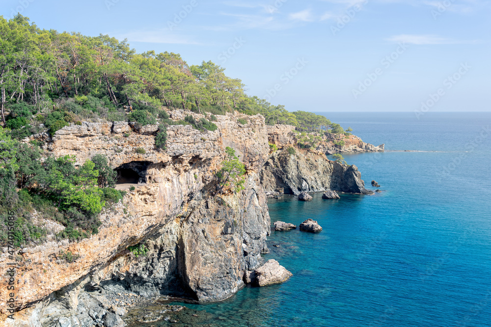Mediterranean seascape with steep wooded coast with cave