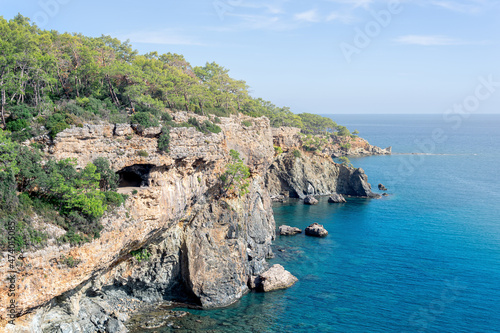 Mediterranean seascape with steep wooded coast with cave