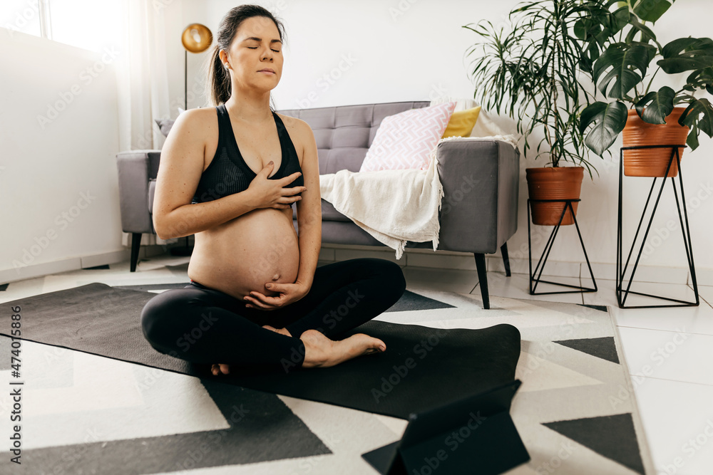 Obraz premium Pregnant woman practicing yoga at home