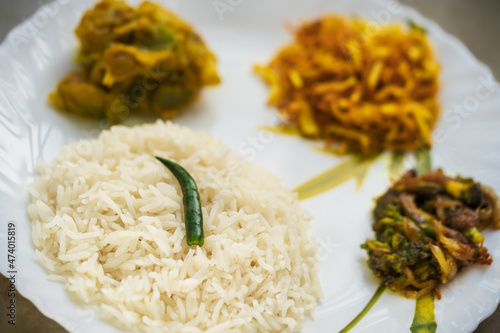 Regional Bengali Homemade Thali. Typical bengali thali background containing rice, dal, potato fries, vegetable curry and a green chilli. Concept for Indian regional food, traditional homemade dish.