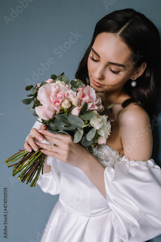 Young bride with a bouquet of flowers in her hands White dress on her body Morning preparations before the engagement ceremony
