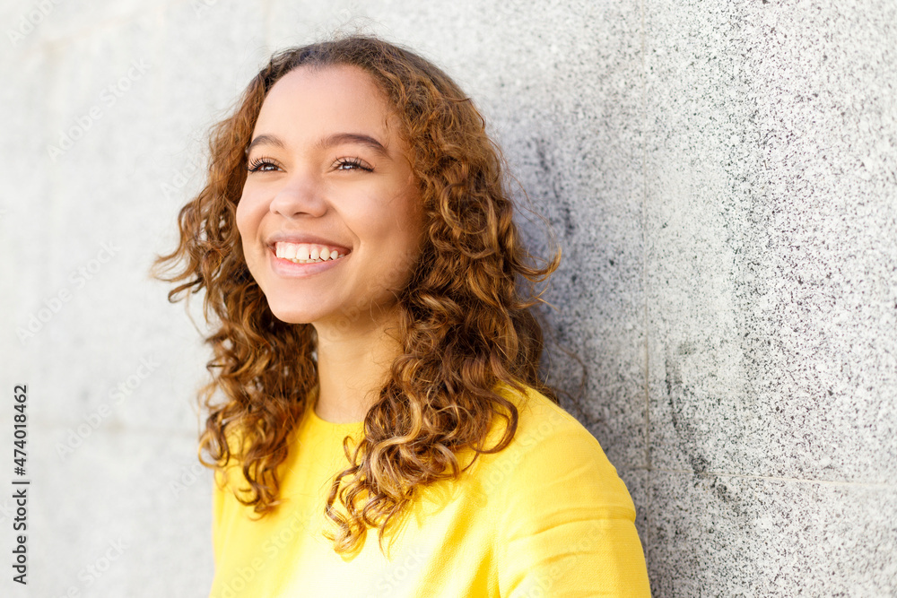 Smiling young woman day dreaming in front of wall Smiling young woman day dreaming in front of wall