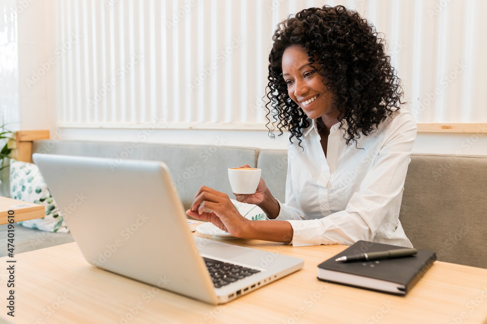 Businesswoman with coffee cup smiling at video call through laptop in cafe Businesswoman with coffee cup smiling at video call through laptop in cafe