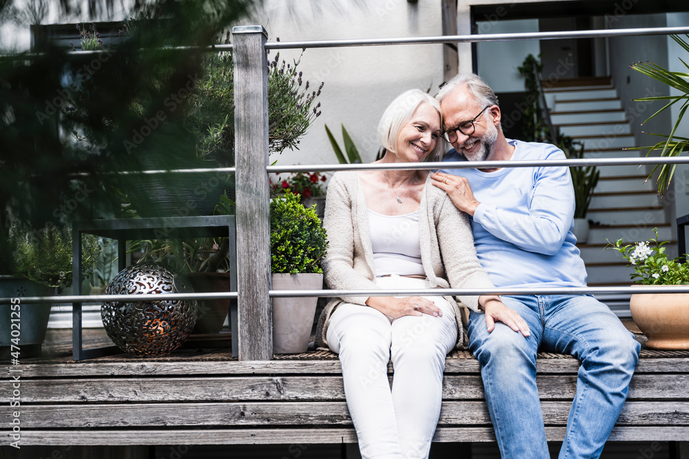 Man smiling while sitting by woman at balcony Man smiling while sitting by woman at balcony