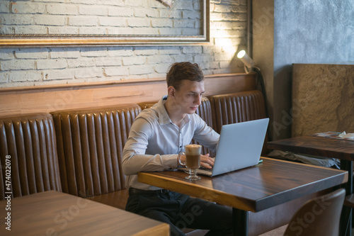 Freelancer working in coffee shop with a laptop. Thinking, solving problems, new ideas. Young business man surfing the net on laptop in a bar. 