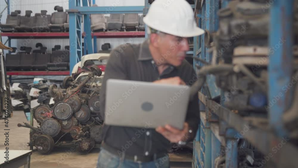 Foreman is checking used car parts in a warehouse on a hot day. Foreman are working in heavy industrial plant engine parts factory. Foreman is checking used car parts in a warehouse on a hot day. Foreman are working in heavy industrial plant engine parts factory.