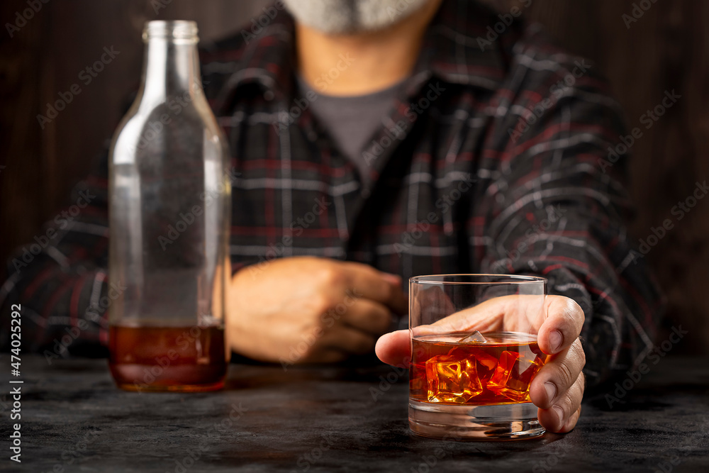 Man holding glass with whiskey.