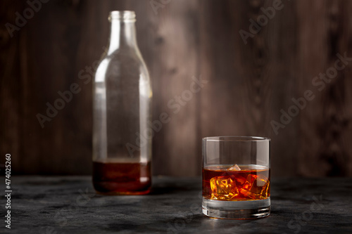 Whiskey bottle and whiskey glass with ice.