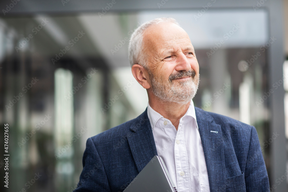 Thoughtful businessman looking away while holding laptop Thoughtful businessman looking away while holding laptop