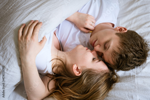 young couple a guy and a girl of Caucasian ethnicity hugging in bed and kissing