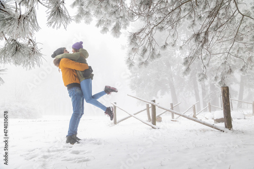Boyfriend lifting girlfriend while spending snowy winter day outdoors