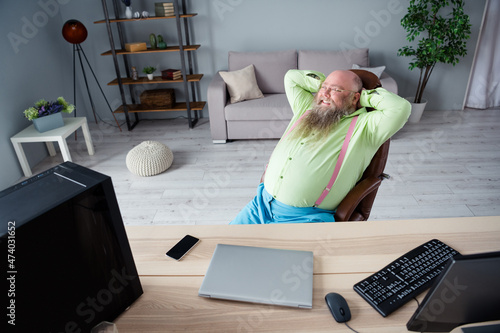 Portrait of attractive cheerful dreamy thick guy finance manager sitting in chair resting at office indoor work place station photo