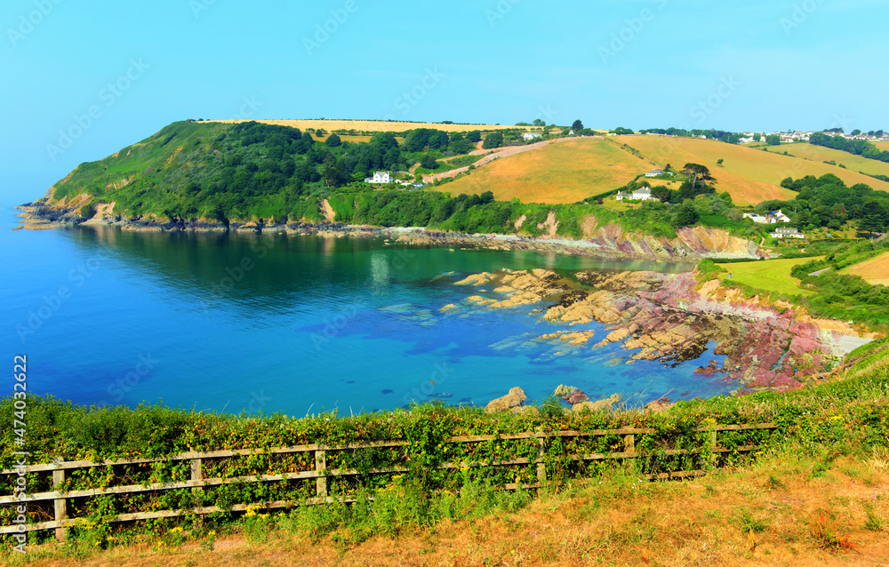 Fototapeta premium Talland Bay Cornwall UK with colourful red and purple rocks and clear sea