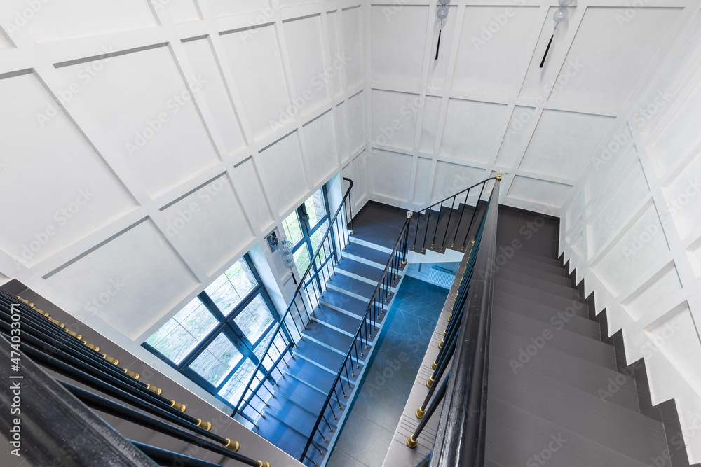 top view of the staircase, the steps of which are made of natural stone, marble and granite, white walls and a large window top view of the staircase, the steps of which are made of natural stone, marble and granite, white walls and a large window