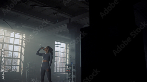 Woman standing in gym with water bottle. Girl drinking water from bottle  © stockbusters