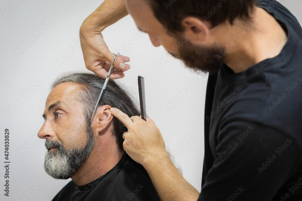 Obraz premium male hairdresser cutting hair for male customer