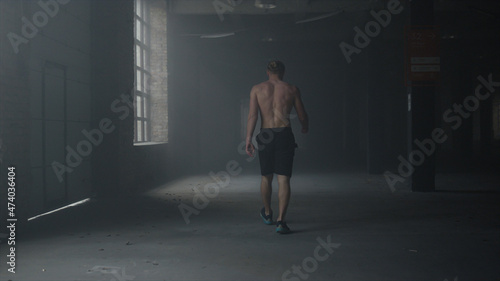 Man walking in building after workout. Athlete warming hands before training 