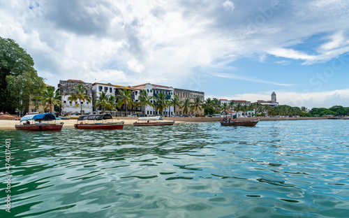 The skyline of Stone Town in Zanzibar seen from the water. sunny day with clouds. travel concept with turquoise indian ocean © mathilde