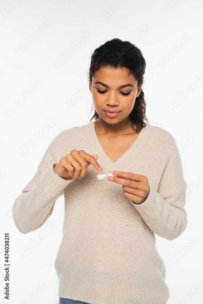 Pretty african american woman holding container with optical lenses isolated on white.