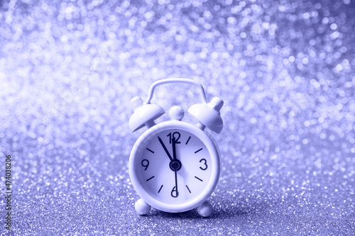 alarm clock on a shiny background. Festive background in toned in color of the year 2022, very peri. selective focus