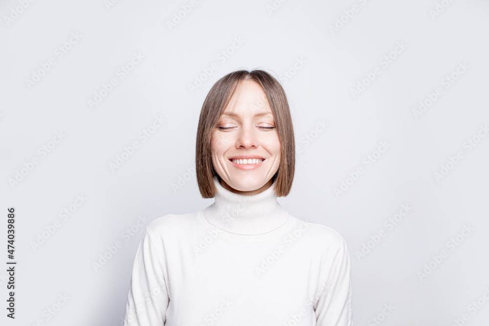 Portrait of a woman with closed eyes closeup wearing white sweater over white Portrait of a woman with closed eyes closeup wearing white sweater over white
