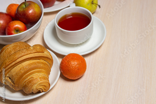 Delicious and healthy breakfast on a white table. A cup of tea with pastries and fruits.