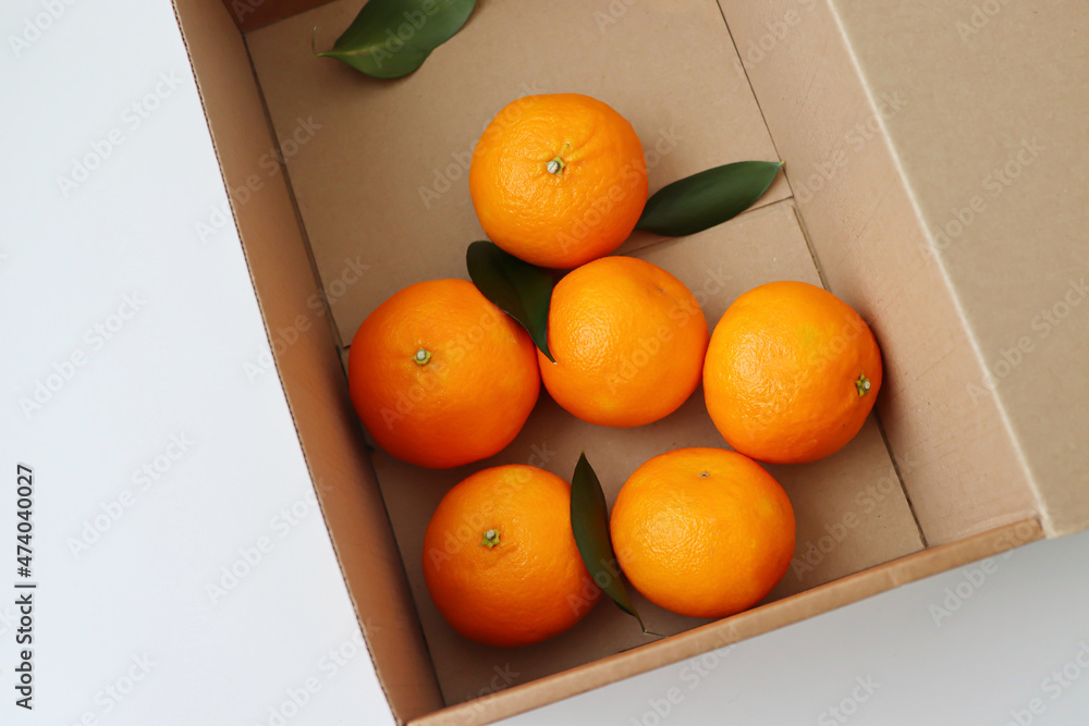 Juicy tangerines lie in a box with leaves