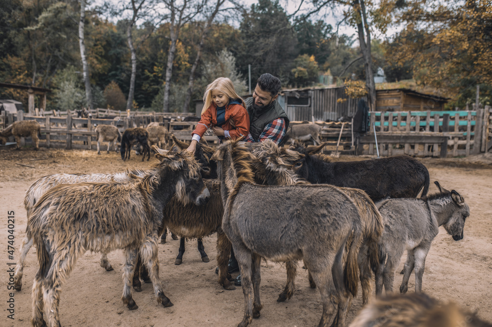 Obraz premium Farmer and his kid spending time with animals in the cattle-pen