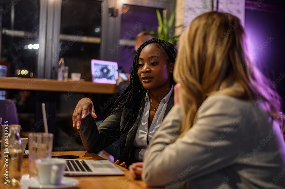 Two businesswoman having a meeting in a cafe while using a laptop Two businesswoman having a meeting in a cafe while using a laptop
