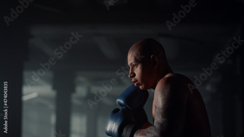 Afro sportsman exercising punch bag in club. Kickboxer doing boxing training © stockbusters