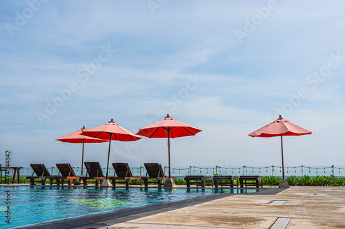 Red umbrella and sun beds at resort and tropical sea with swimming pool for holiday vacation © pushish images