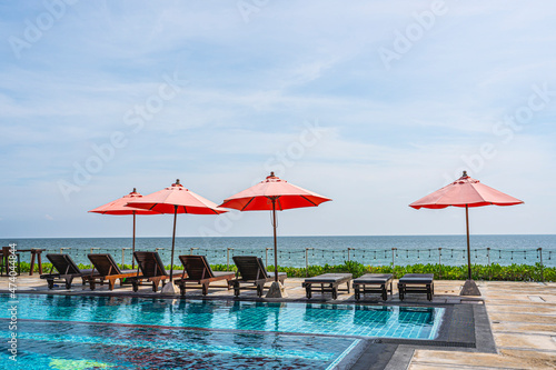 Red umbrella and sun beds at resort and tropical sea with swimming pool for holiday vacation © pushish images