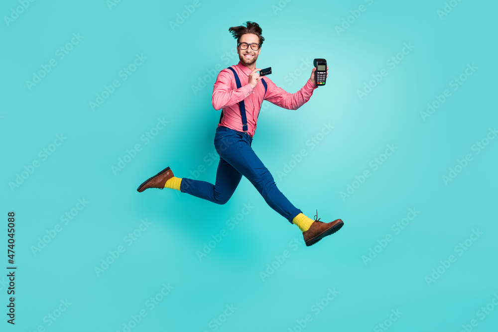 Photo of sweet pretty guy dressed pink shirt spectacles holding credit card atm jumping high isolated turquoise color background