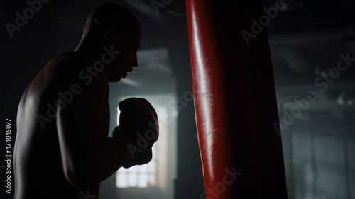 Afro boxer man hitting punching bag. Sportsman training punches in gym photo