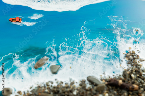 Resin art background. Epoxy art composition with blue waves, boat and stone beach.