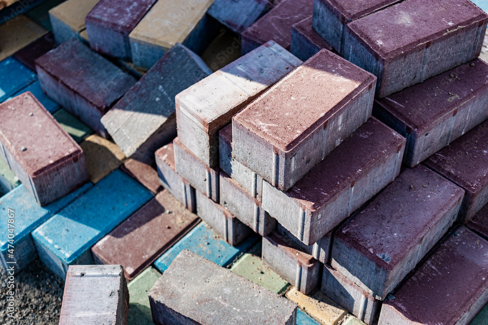 Multi-colored paving slabs. Pavement repairs and paving slabs laying on the roadway, with tile cubes in the background. Laying of paving slabs in the pedestrian zone of the city, improvement. Multi-colored paving slabs. Pavement repairs and paving slabs laying on the roadway, with tile cubes in the background. Laying of paving slabs in the pedestrian zone of the city, improvement.
