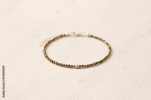 Pyrite bracelet. A bracelet made of stones on a hand from natural stone Pyrite. Bracelet made of natural stones. Handmade jewelry. Handmade thin bracelets on light modern background