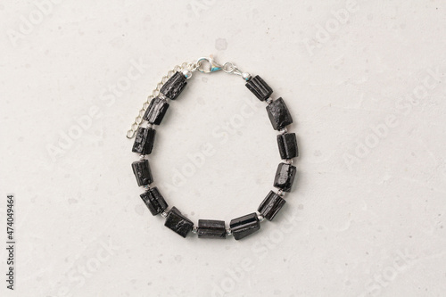 Black tourmaline, sherl bracelet. Bracelet made of stones on hand from natural stone Black tourmaline, sherl on light concrete modern background. Magic jewelry, lithotherapy and stone therapy photo