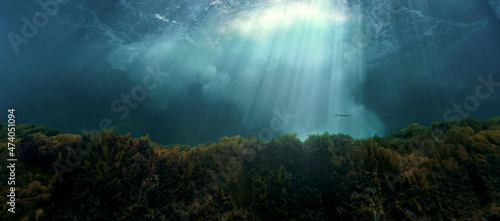 Underwater photo of rays of light breaking through the surface and the waves