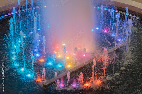 Fototapeta Naklejka Na Ścianę i Meble -  A fountain with streams illuminated by multicolor backlights. Multi-colored fountain. Musical fountain