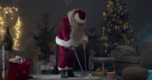 Santa Claus cleaning messy living room in evening