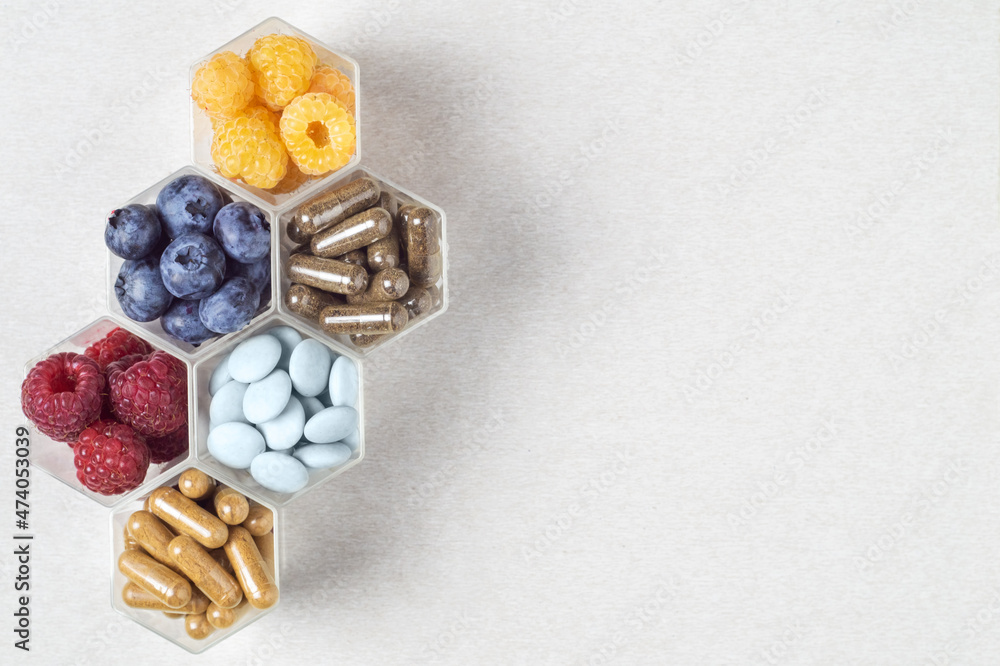 Fresh berries, pills and capsules in honeycomb like hexagonal jars Fresh berries, pills and capsules in honeycomb like hexagonal jars