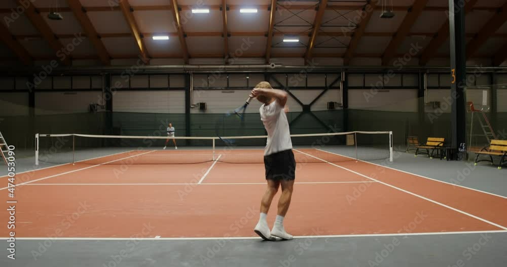 Young man and woman play tennis on an indoor tennis court Young man and woman play tennis on an indoor tennis court