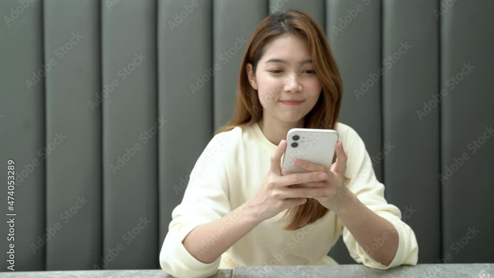 Happy young Asian woman sitting in cafe using smartphone enjoy chatting with friend. Happy young Asian woman sitting in cafe using smartphone enjoy chatting with friend.