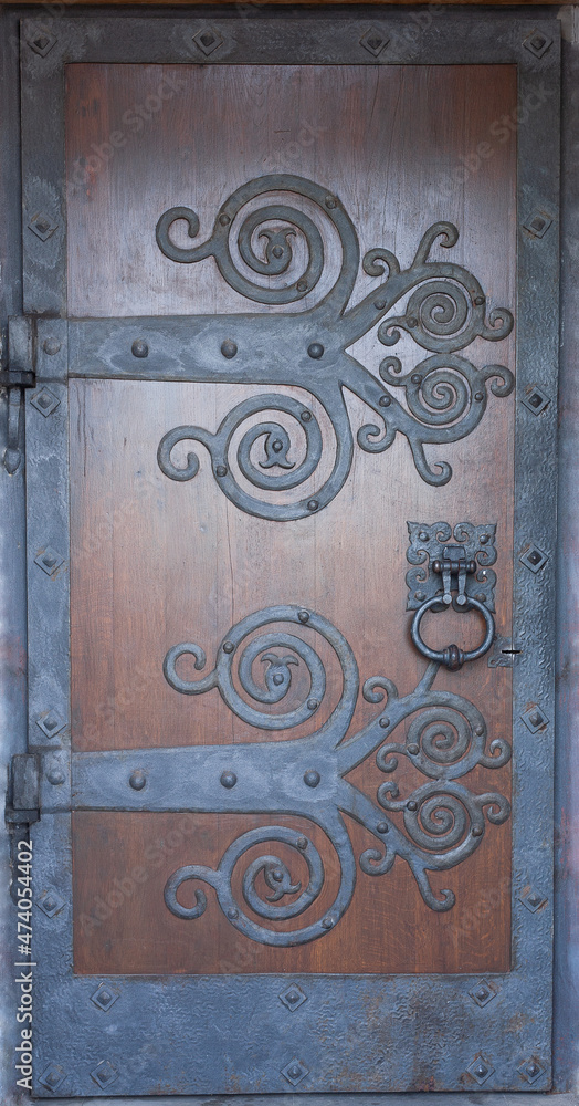 Old wooden doors of the monastery with a decorative metal hinges. Door of the church with carvings. Old wooden doors of the monastery with a decorative metal hinges. Door of the church with carvings.