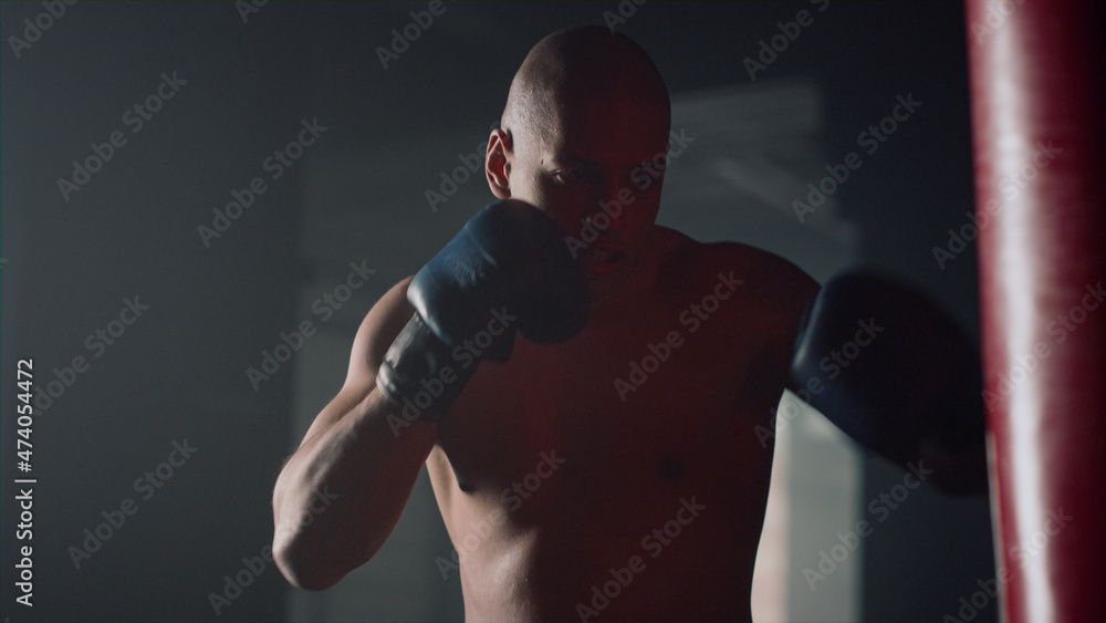 Professional boxer punching bag in gym. Sports man boxing in sports club