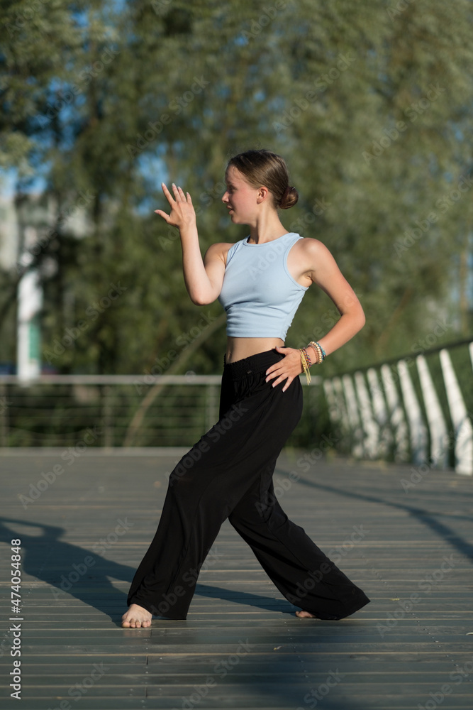The girl dances beautifully on the embankment of the lake