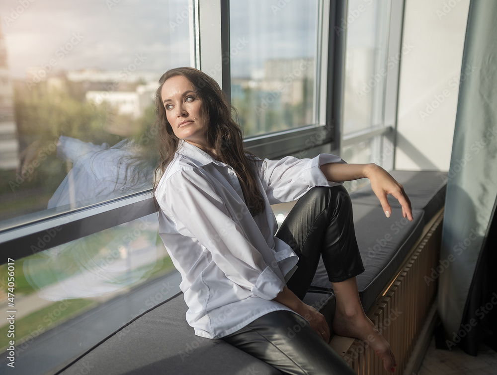 Young beautiful brunette with long hair. In the studio near the window. Young beautiful brunette with long hair. In the studio near the window.