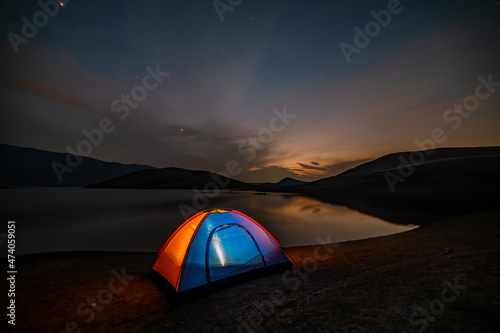 Tent in the lakeshore in the beautiful mountains. Night camping.