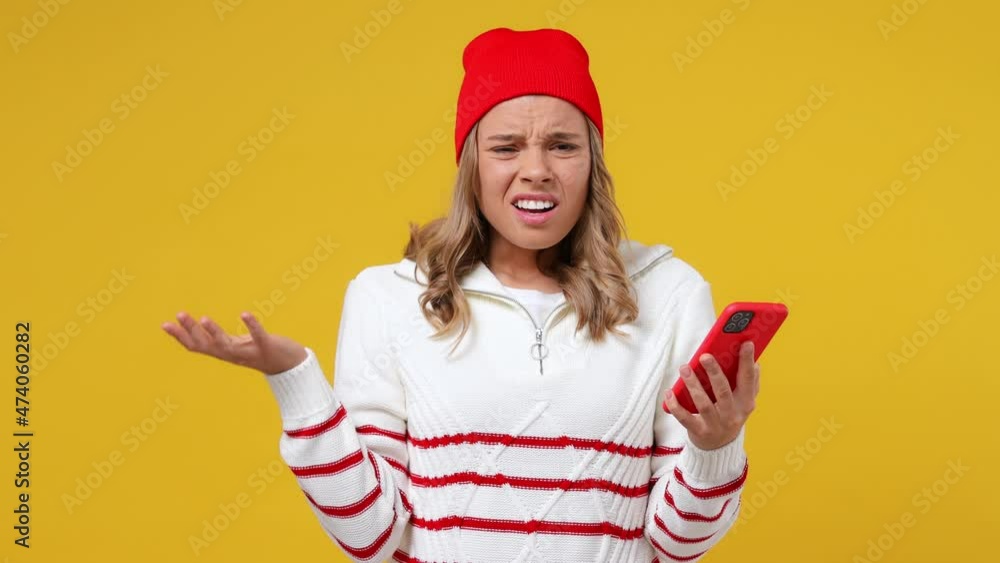 Sad irritated young girl teen student wears striped white shirt hat using mobile cell phone swear hears fake news unexpected rumor has some problems isolated on plain yellow background studio portrait Sad irritated young girl teen student wears striped white shirt hat using mobile cell phone swear hears fake news unexpected rumor has some problems isolated on plain yellow background studio portrait